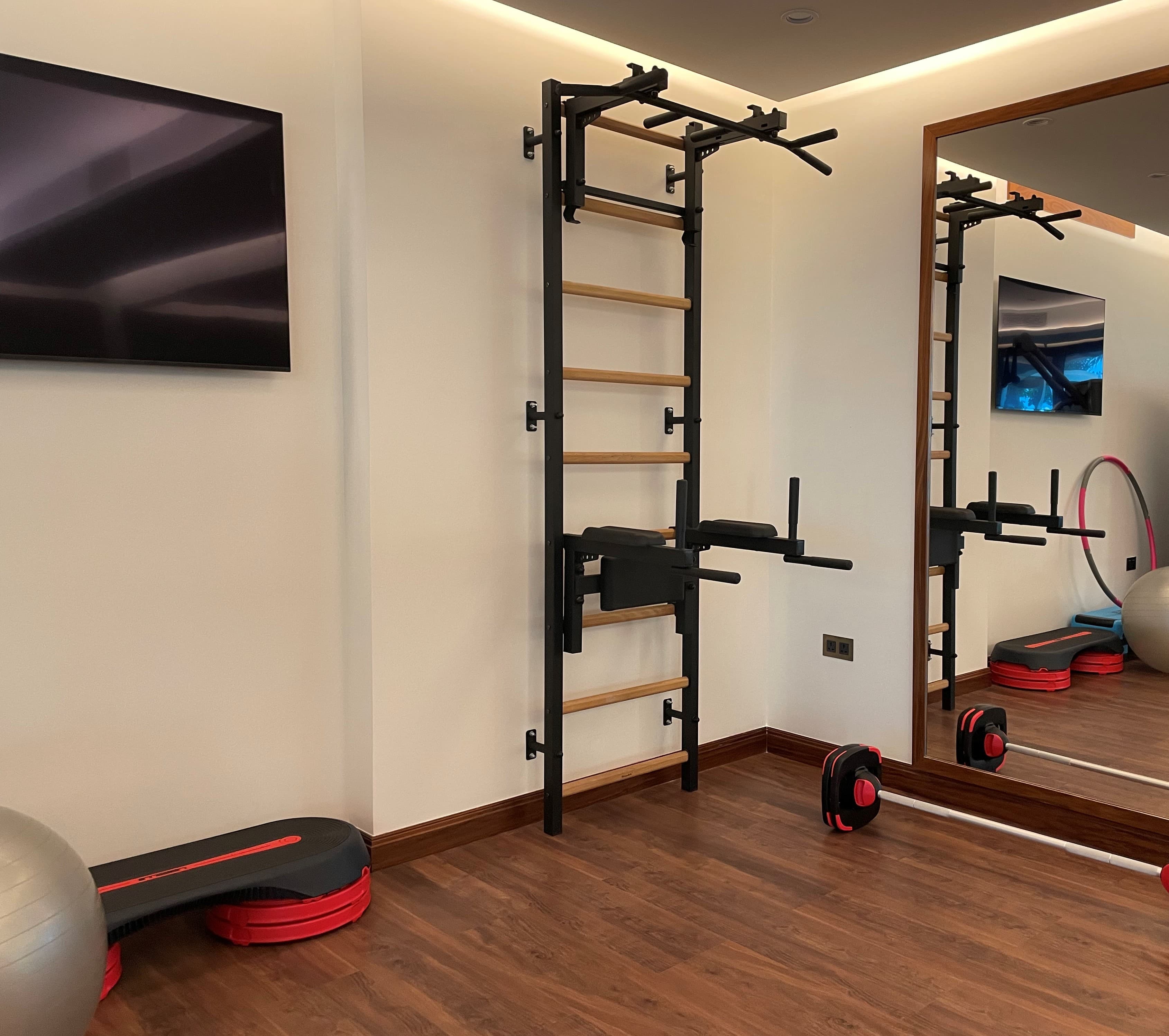 BenchK wall bars with an overhead pull-up bar mounted in the corner of a home gym, used for daily hanging