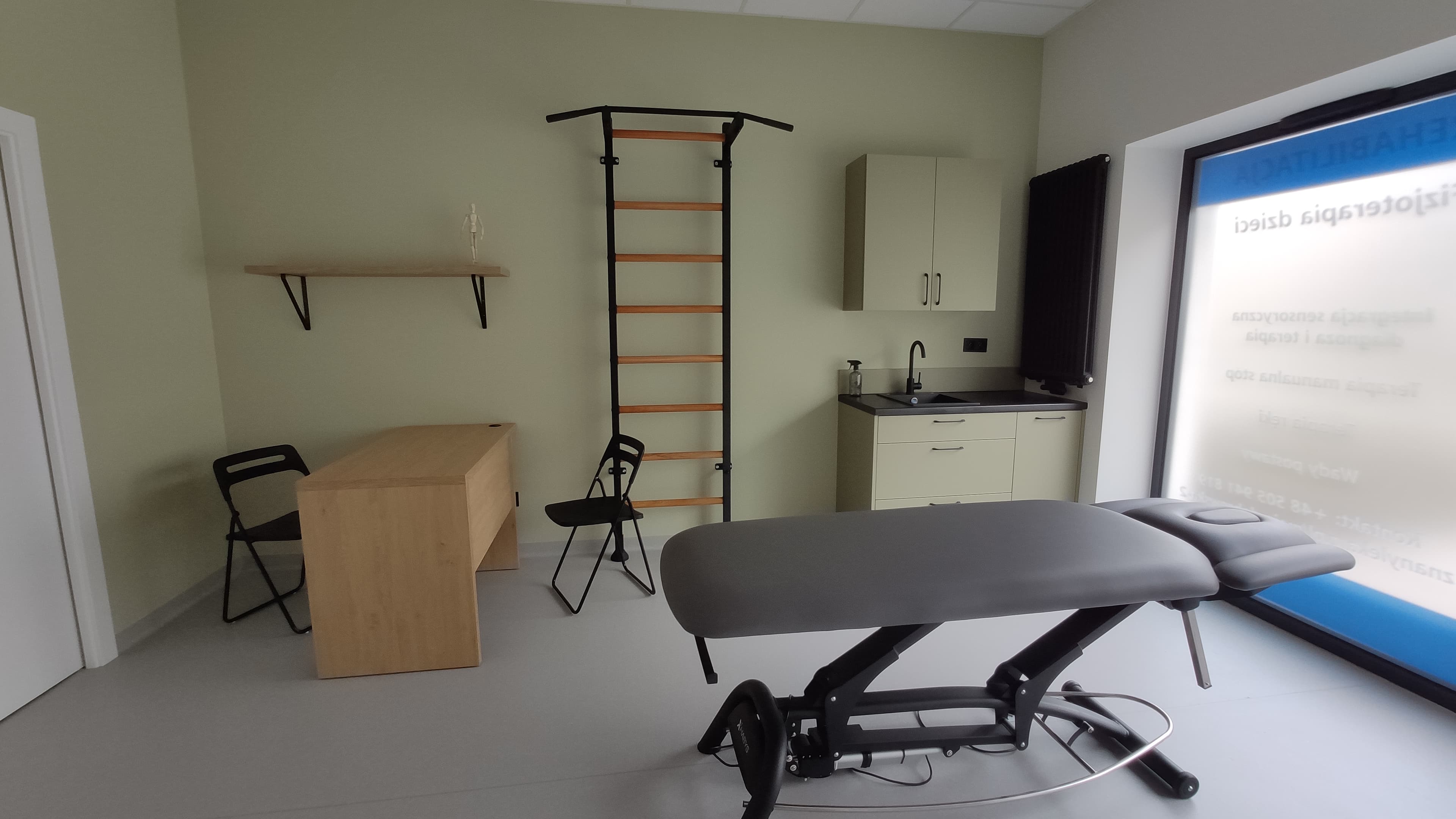 A physiotherapy clinic treatment room with wall bars, a treatment table, and rehab equipment