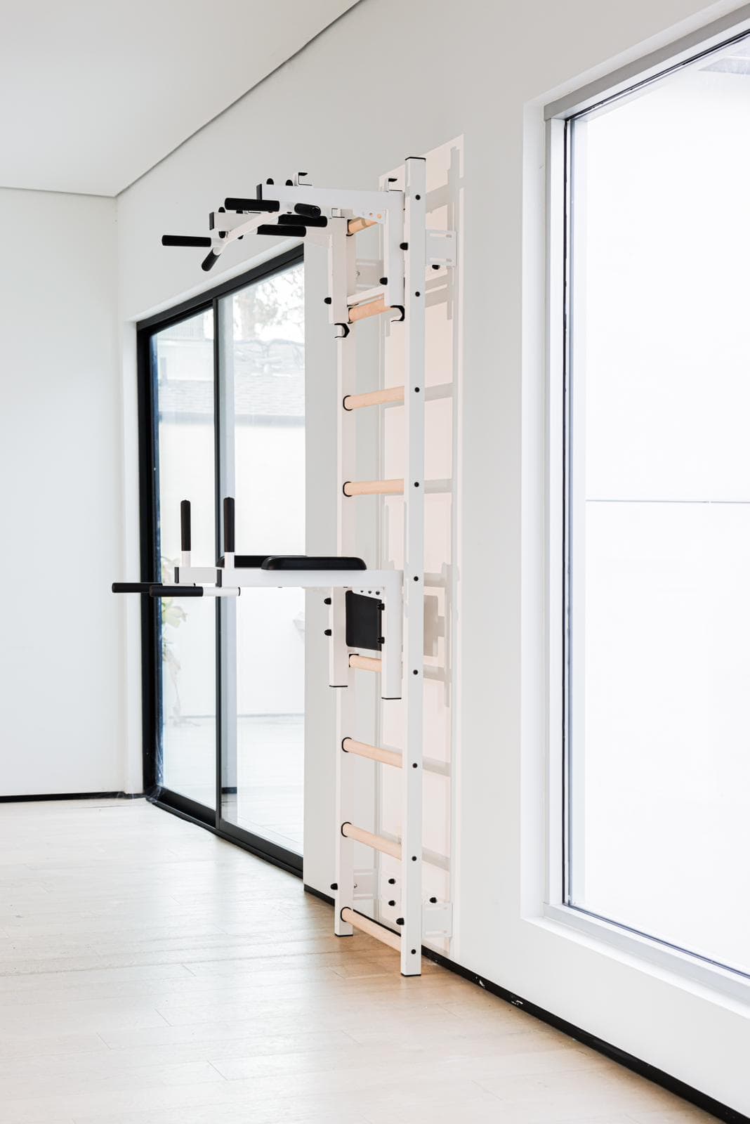 White BenchK wall bars with dual pull-up bar attachments mounted in a bright, minimalist room